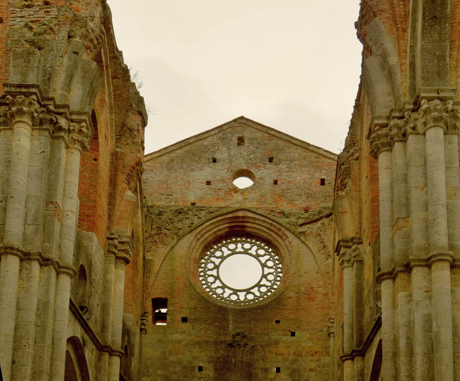 Interno dell’Abbazia di San Galgano senza tetto con archi e rosone